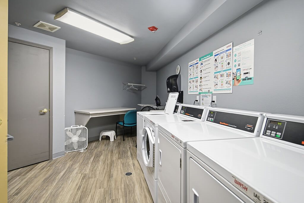 A laundry room with washers and dryers and a fan.